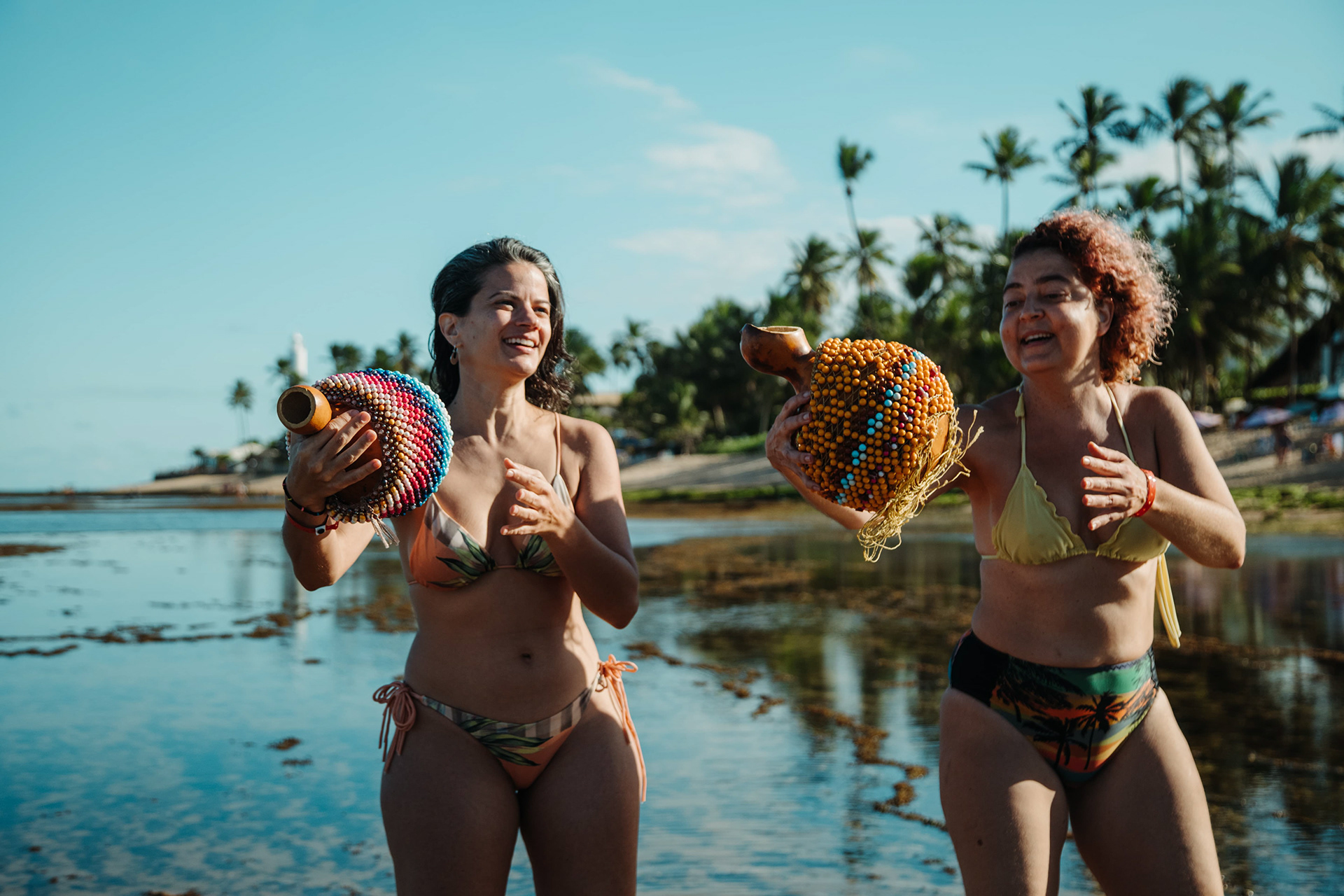 Mulheres vestidas de branco dançando na praia, ritual de Agbezeiras