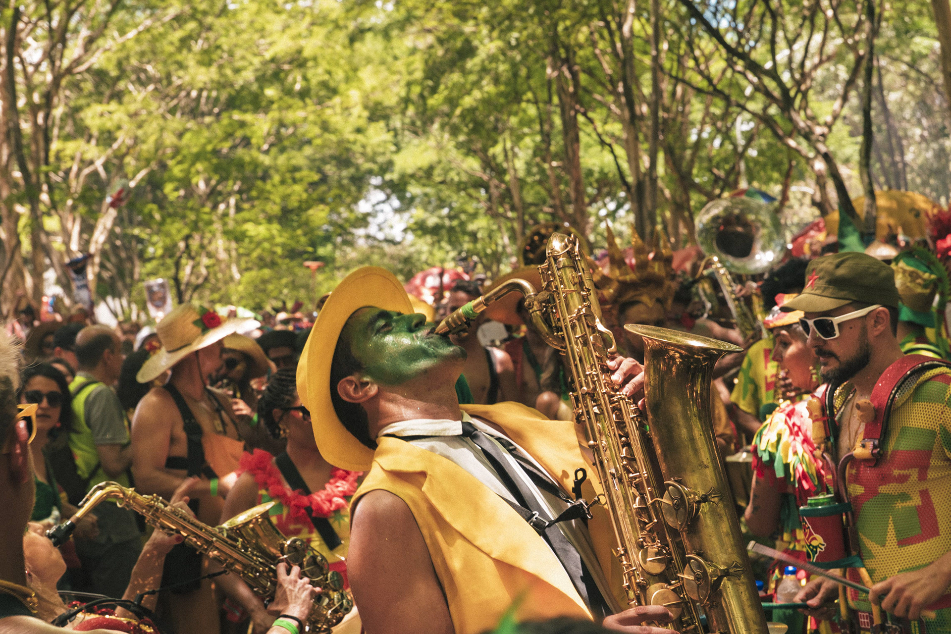 Figura mascarada em meio à vegetação durante folia de carnaval