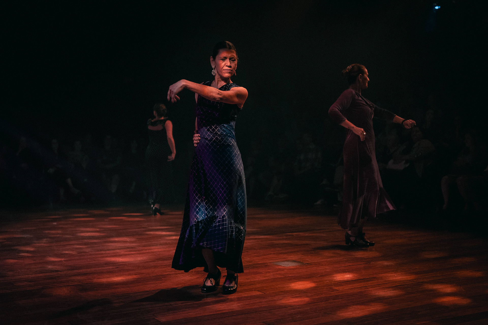 Bailarina de flamenco com braço erguido em palco escuro
