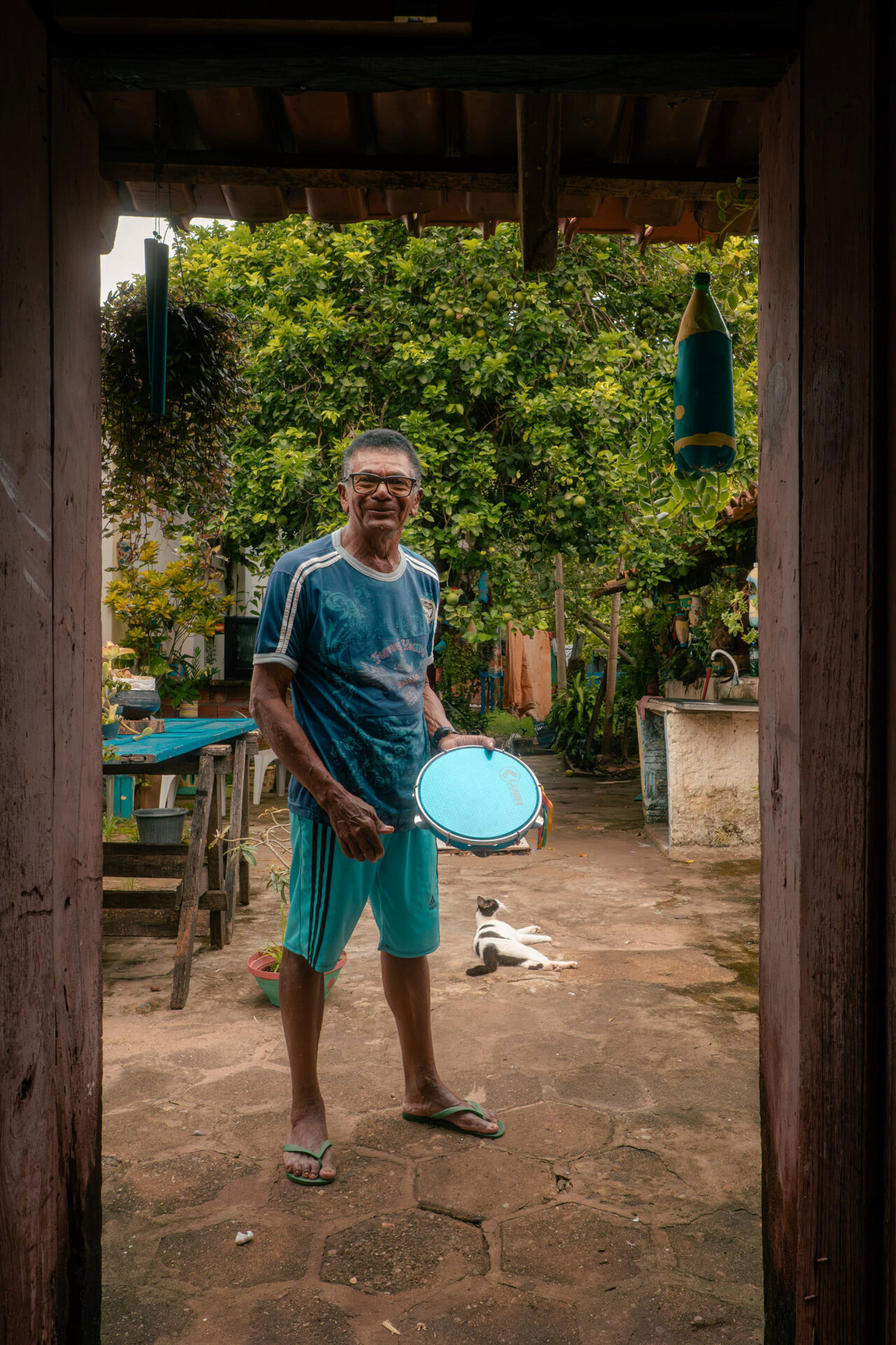 Retrato de homem segurando objeto redondo na porta de uma casa, Maranhão
