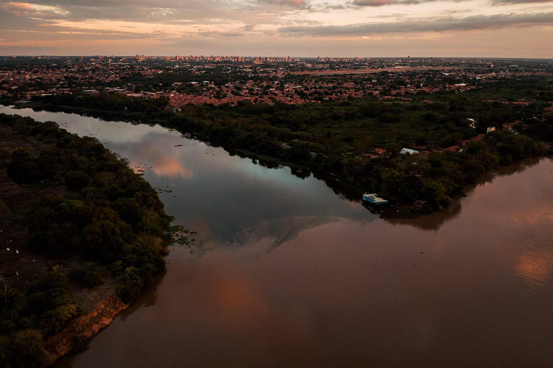 Vista aérea de rio ao entardecer com céu em tons alaranjados, Piauí