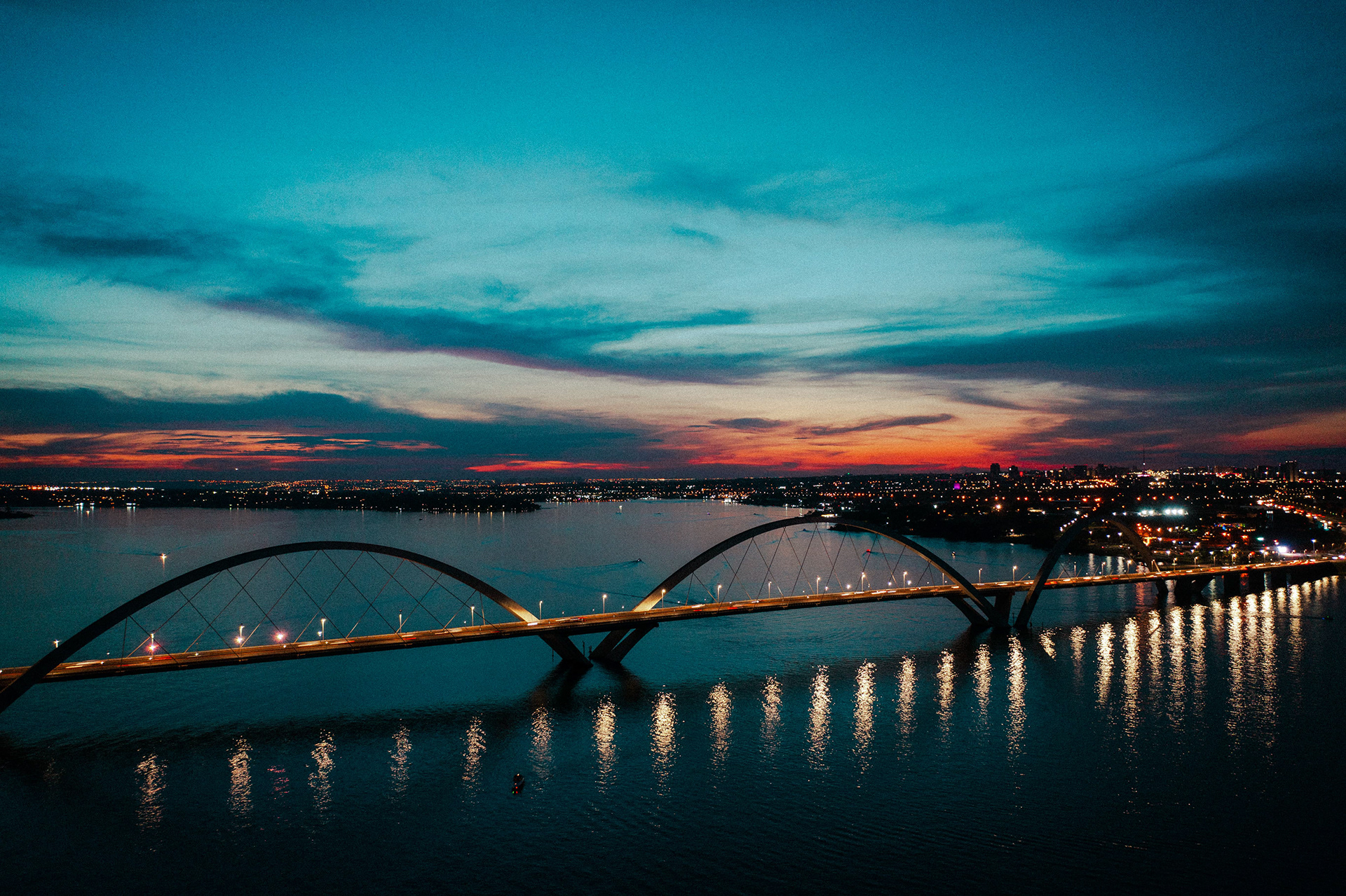 Ponte JK iluminada à noite, refletida no Lago Paranoá, Brasília